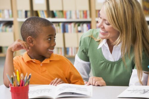 Kindergarten teacher helping student with reading skills Kindergarten teacher helping student with reading skills